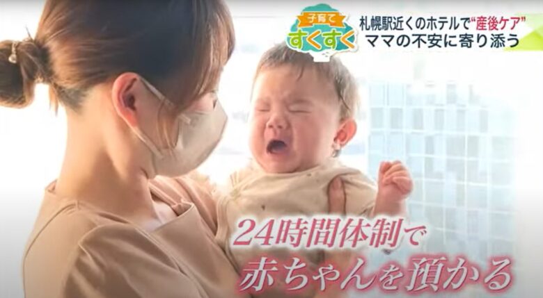 助産師が泣いている赤ちゃんを優しく抱っこしている様子。24時間体制で赤ちゃんを預かる産後ケアホテルのシーン