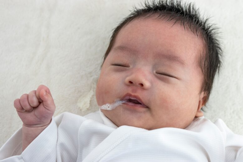 口元にミルクをつけながら眠っている赤ちゃんの顔のアップ