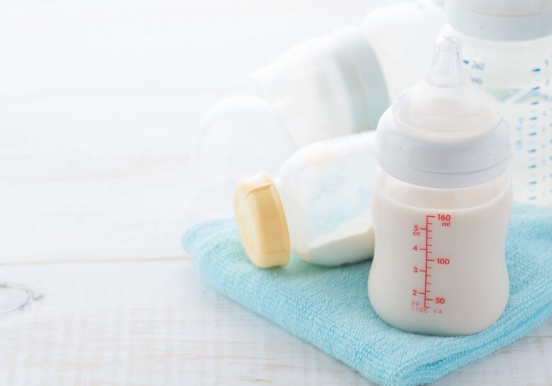 青いタオルの上に置かれた、ミルク入りの哺乳瓶
